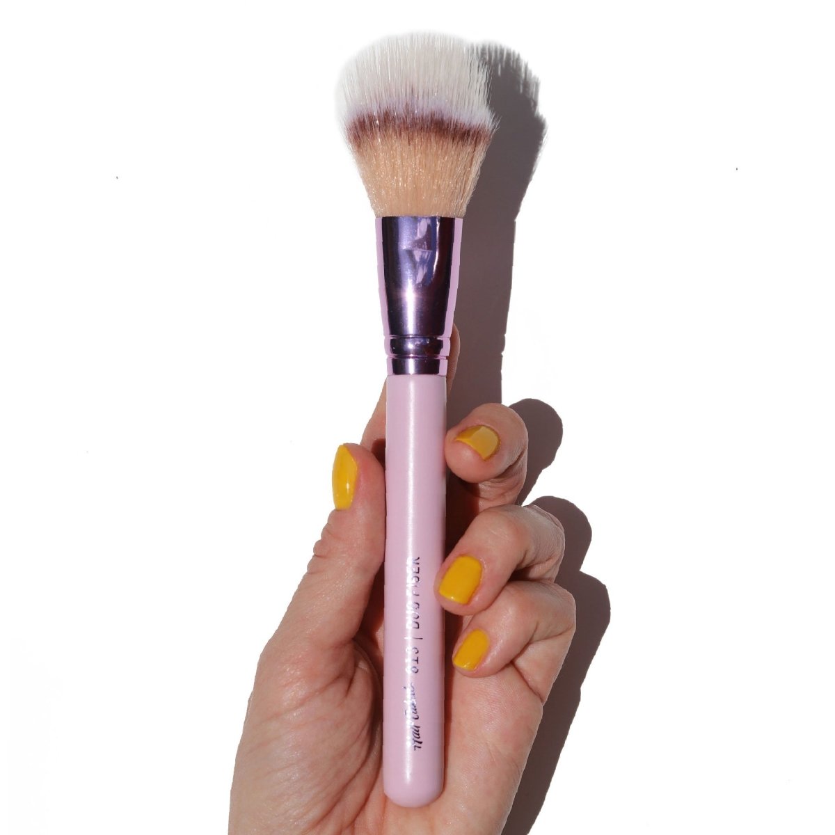 shiny purple tan brown and white blush brush in hand with yellow fingernails - duo fiber - half caked makeup