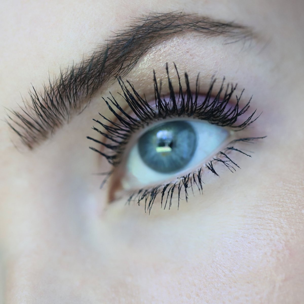 closeup of blue eyes with black mascara on - totally tubular mascara, the ultimate - half caked makeup
